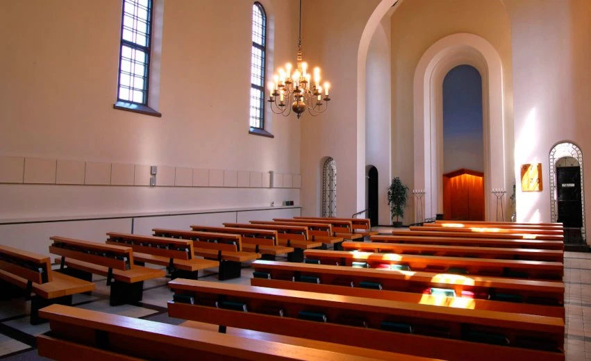 Hietaniemen krematoriokappelin iso kappeli. Kuvassa etualalla penkkirivit, niiden yläpuolella kynttiläkruunu, kappelin takaosassa korkea ja kaareva kulkuaukko, jonka sivuilla kaksi pienempää kulkuaukkoa.